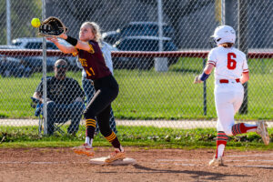 Milford junior Isabella Watson stretches out her glove to get Smyrna senior Alyssa Spicer out at first.