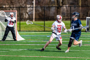 Photo Gallery: Smyrna vs Friends Boys Lacrosse 11 Smyrna defenseman senior Jake Supinski (18) defends against Friends Rhys Butler (8) as Smyrna goalie junior Boe Evans (35) looks on from the net