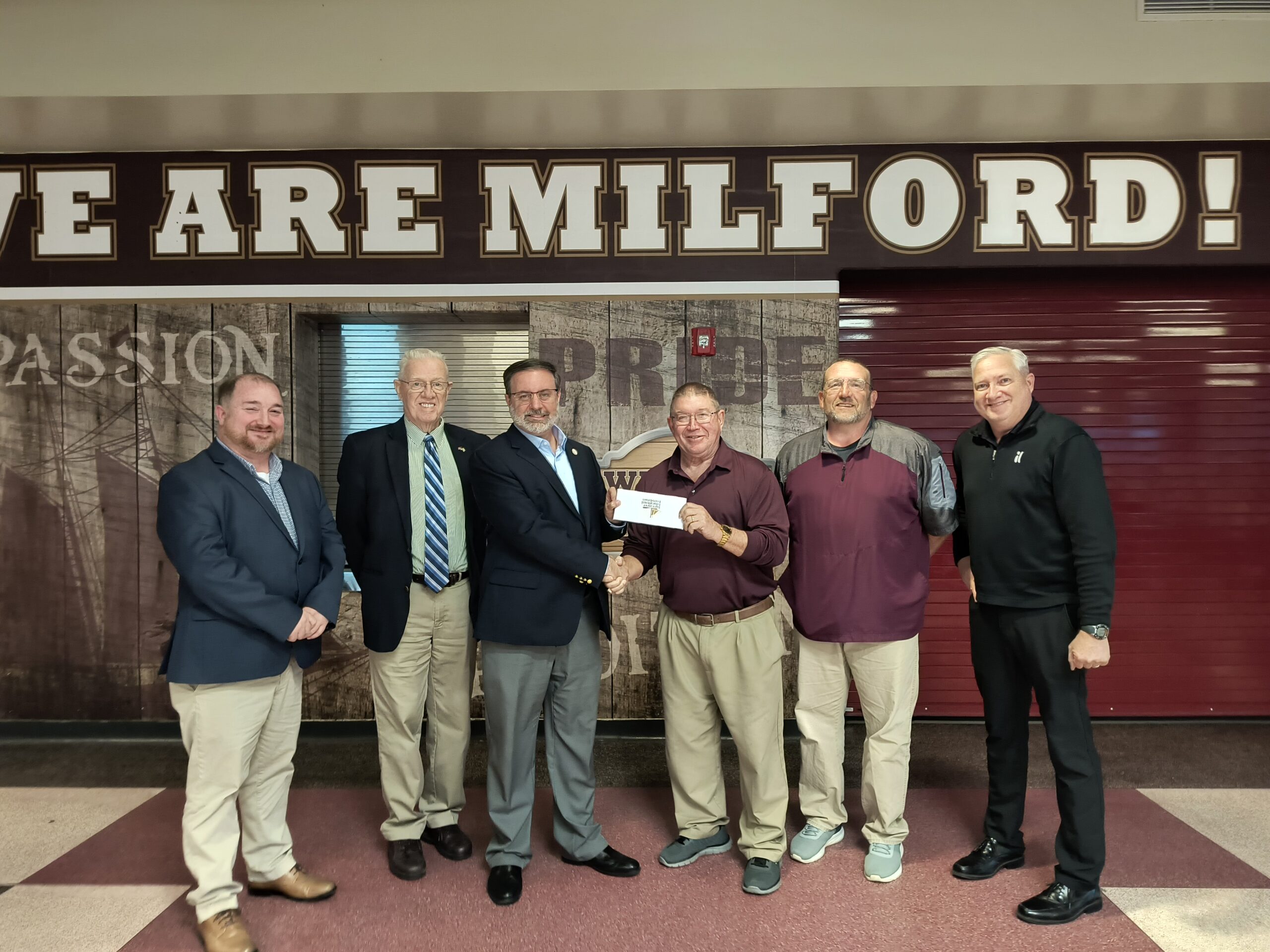Matt Bucher presented a $15,000 Buccaneer Educational Foundation gift to Milford 12th Man Gridiron Club president Jack Simon at the March 23 Milford School Board meeting on behalf of an anonymous family. (Photo courtesy of Buccaneer Educational Foundation.)