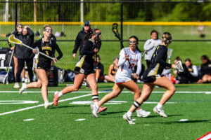 Smyrna freshman Kennedy Marks runs down field with three Pandas around her.