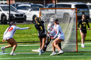 Padua freshman Emily Hill gets a shot off despite the tough defense from Smyrna in front of the cage.