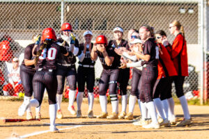 Polytech sophomore Emma Shleton is welcomed at home plate by her teammates after hitting one of her two home runs.