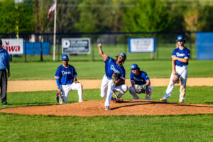 Dover senior Carter Bean warms up with the infield watching from behind the mound.